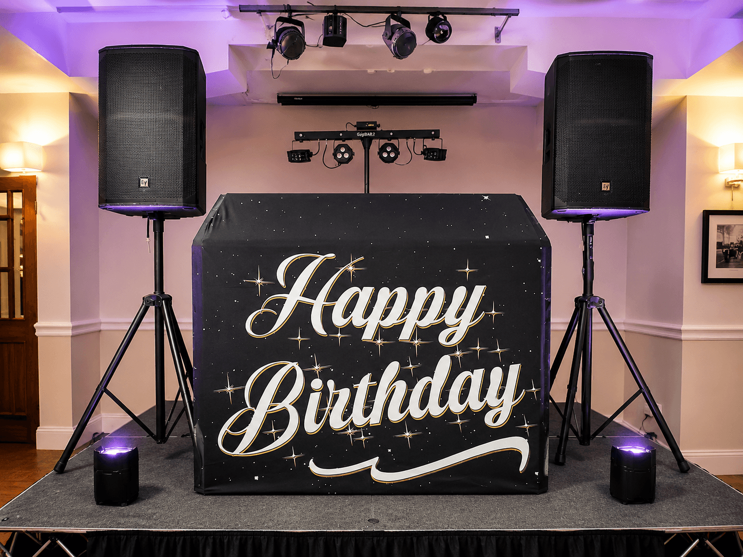 Professional DJ booth with speakers and uplighting at a celebration from Cameron's Events